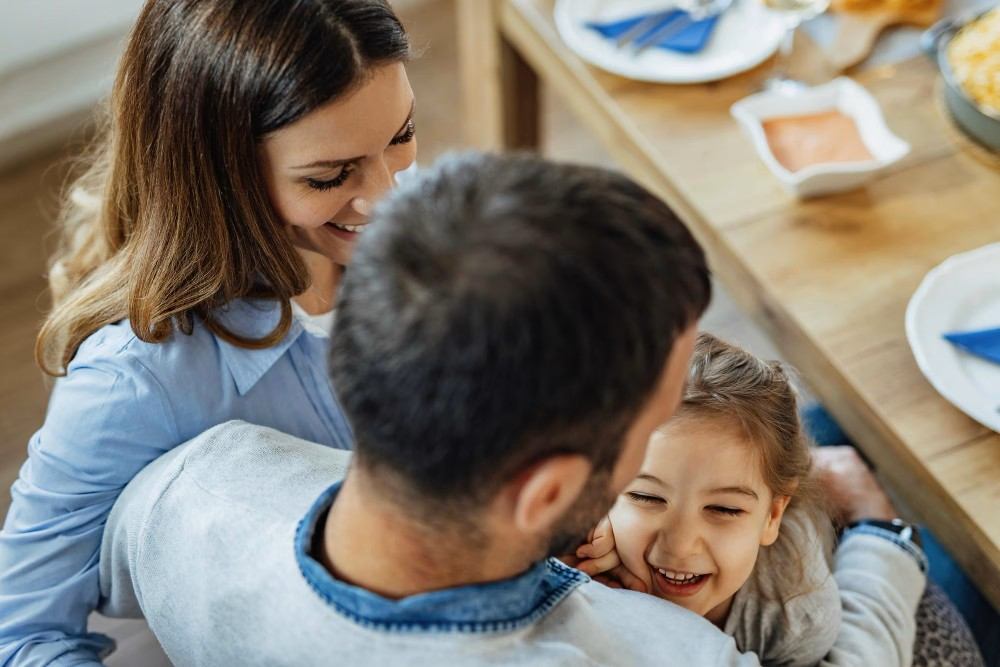 Pais e filha sorrindo no café da manhã